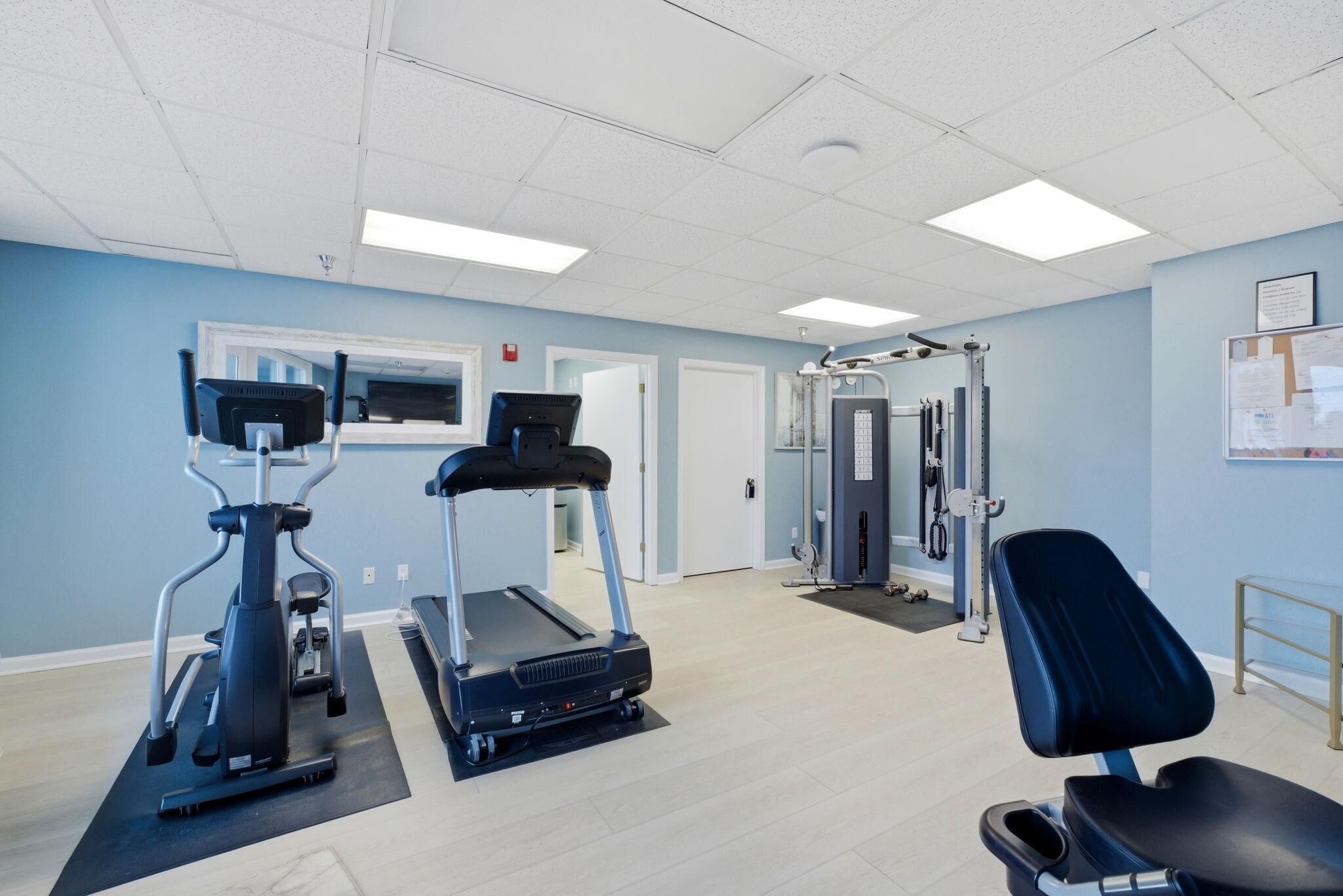 A fitness center with treadmills, a weight machine, and a black exercise chair.