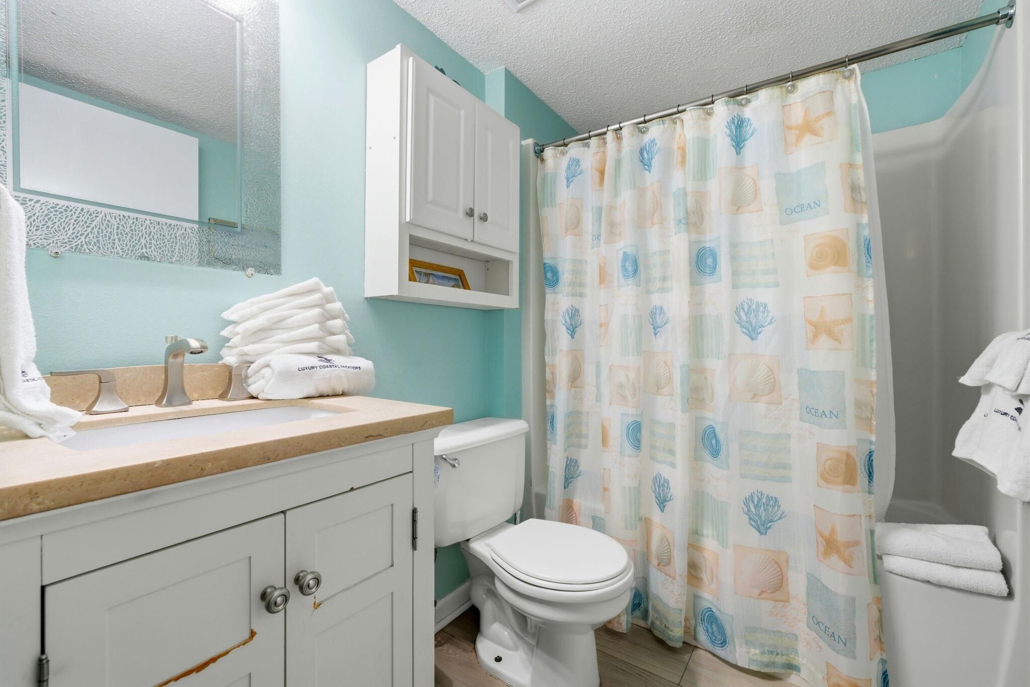 A bathroom with a toilet, sink, and cabinet.