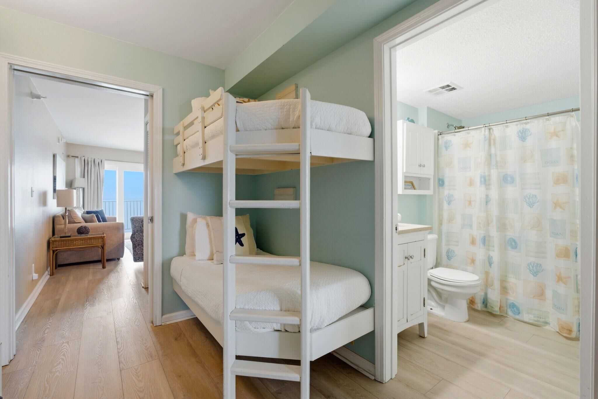 A bunk bed room with a bathroom and a living area.