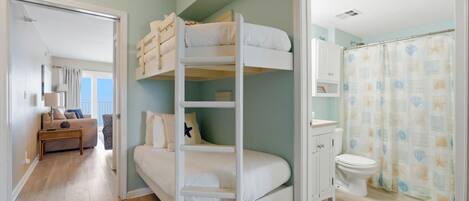 A bunk bed room with a bathroom and a living area.