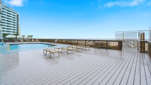 Een terras met een zwembad, ligstoelen en uitzicht op de oceaan.