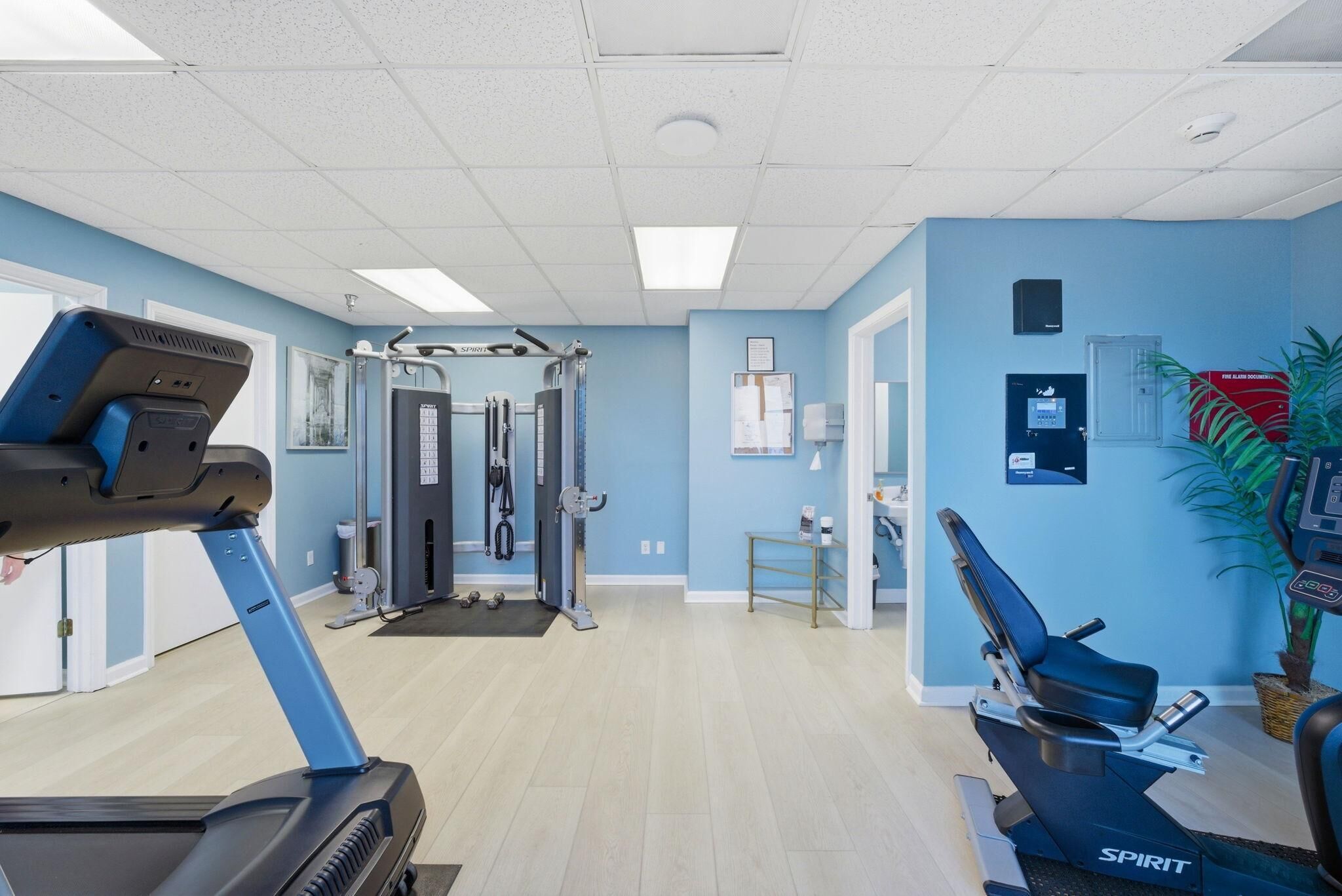 A fitness center with cardio equipment, weight machines, and a wall-mounted sign.