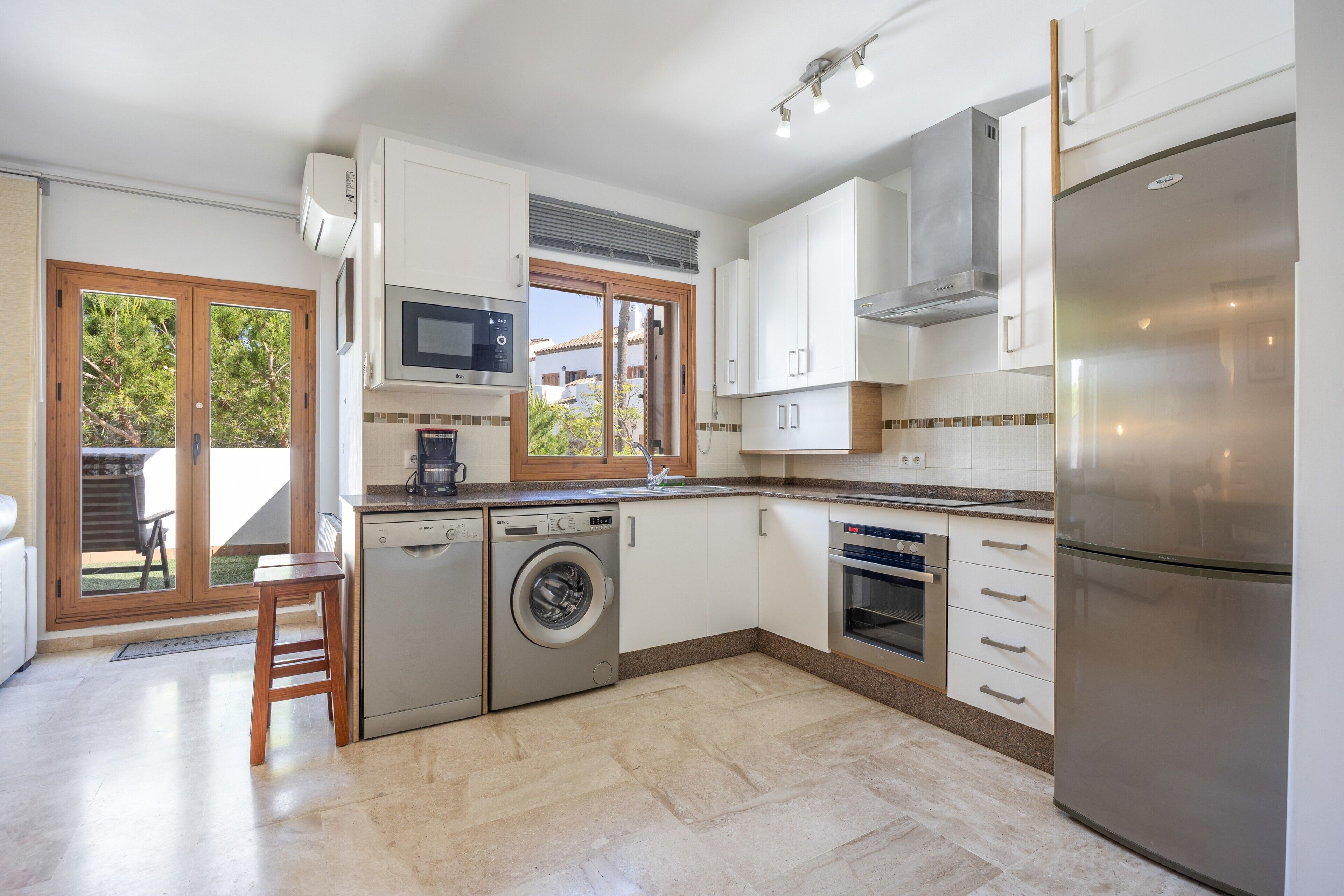 A modern kitchen with a dishwasher, washing machine, microwave, oven, and a large refrigerator.