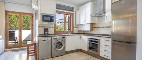 A modern kitchen with a dishwasher, washing machine, microwave, oven, and a large refrigerator.
