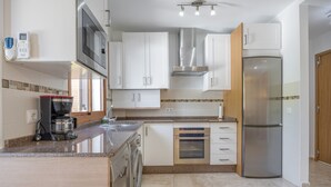 A modern kitchen with a built-in oven, microwave, stainless steel refrigerator, and a coffee maker. - Levante Sancti Petri Apartment with Shared Pool, Wi-Fi, and Air Conditioning (Chiclana de la Frontera)