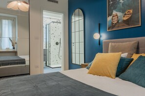 Ein Schlafzimmer mit Bett, Dusche, Spiegel und einem Gemälde mit Booten.
