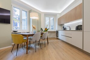 Eine moderne Küche mit Essbereich, Holzschränken und einem großen Fenster.