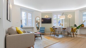 En moderne stue med sofa, spisebord, stole og fjernsyn.
