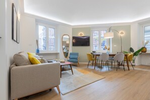 Ein modernes Wohnzimmer mit Sofa, Esstisch, Stühlen und Fernseher.