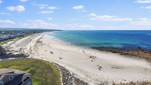 Una playa con cielo despejado, orilla arenosa y algunas personas.