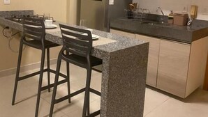 Une cuisine dotée d’un îlot en granit, de tabourets de bar, d’un réfrigérateur, d’un four à micro-ondes et d’un évier.
