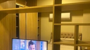 Un téléviseur posé sur un meuble en bois dans une pièce dotée d’étagères intégrées.