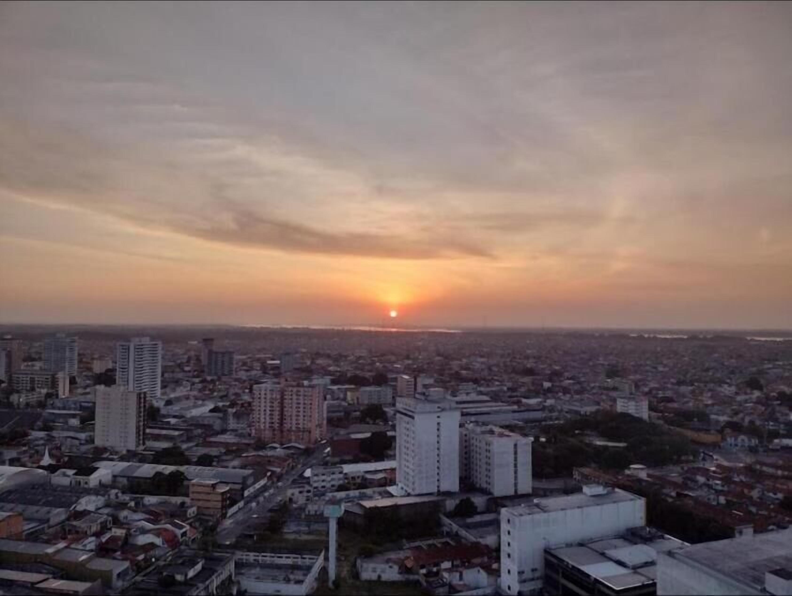 A cityscape at sunset with high-rise buildings and a clear sky.