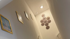 En trappa med trästeg och vita väggar, dekorerad med inramade bilder och ett väggkonstverk med blommotiv.