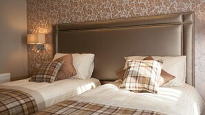 Habitación de hotel con una cama grande, dos almohadas, cabecero y una lámpara de pared.