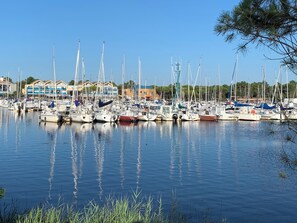 A marina with multiple sailboats docked, surrounded by buildings and greenery. - Lakeside apartment with enclosed garden, dog allowed, electric charger (Hourtin)