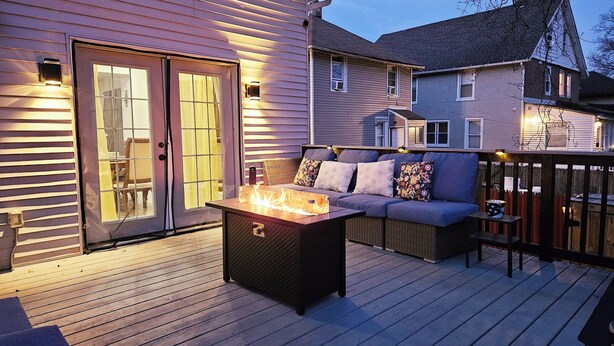 A deck with a fire pit, outdoor seating, and a sliding glass door leading to an interior space. - Tudor Lux (East Lansdowne)