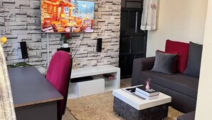Un salon moderne avec un mur en pierre, un téléviseur à écran plat, un canapé, une table basse et un bureau avec une chaise.