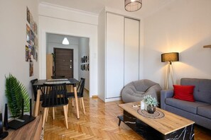Un soggiorno moderno con zona pranzo, un divano grigio, un cuscino rosso, un tavolino in legno e una lampada.