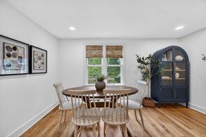 A dining area with a round table, four chairs, a vase, and a cabinet. - 2BR Cottage w/ Backyard | 10 Min Walk to Kirkwood (Bloomington)