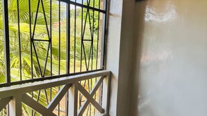 A room with a window featuring a metal grille and a white wooden balcony railing. - A Calm, Elegant 3BR retreat in Milimani, Kitale (Kitale)