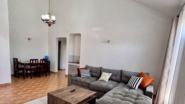 A living room with a sectional sofa, a wooden coffee table, and a patterned rug. - A Calm, Elegant 3BR retreat in Milimani, Kitale (Kitale)