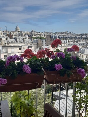 Ein Balkon mit Blumenkästen mit Blick auf eine Stadtlandschaft mit historischen Gebäuden und einer Kuppel.