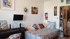 Ein Schlafzimmer mit einem Bett, einem Fernseher, einem Schreibtisch und verschiedenen Wanddekorationen.