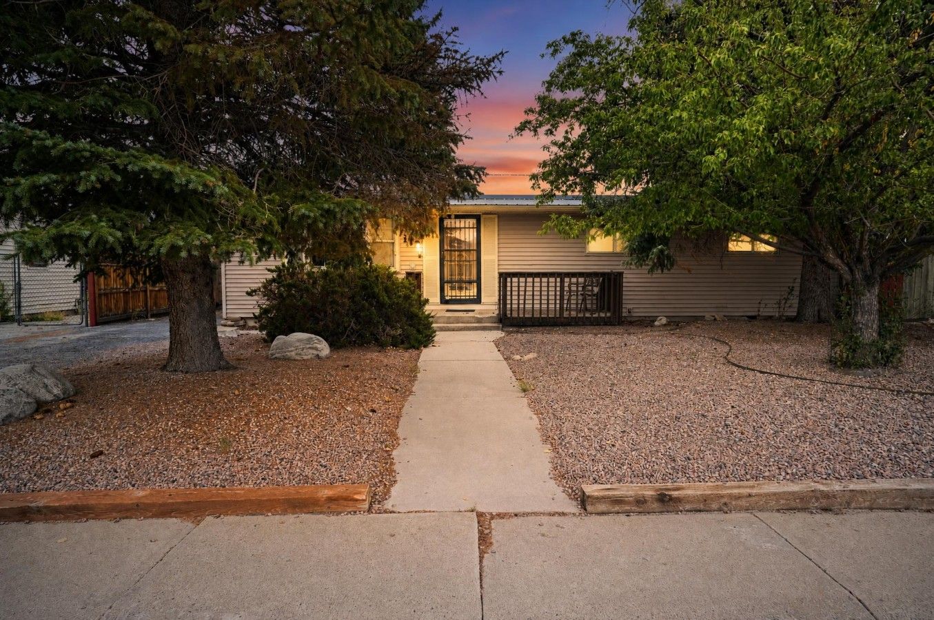 A residential house with a front yard, a driveway, and a large tree on the left.