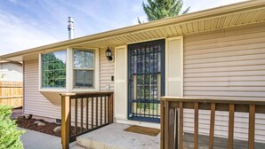 Einbungalow mit Veranda, schwarzem Eingang und Schornstein.
