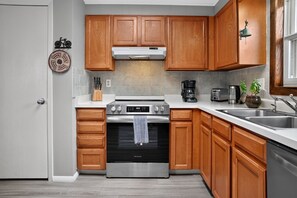 Eine moderne Küche mit Holzschränken, Edelstahlgeräten und einem eingebauten Backofen.