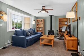 Ein gemütliches Wohnzimmer mit einem blauen Sofa, einem Holztisch, einem Schaukelstuhl und einem Kamin.