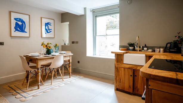 Een moderne keuken met houten kastjes, een inbouwvaatwasser en een raam dat natuurlijk licht binnenlaat.