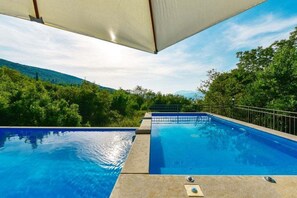 Ein Swimmingpool mit Blick auf grüne Bäume und Hügel.
