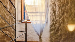 A staircase leading to a room with a window covered by sheer curtains, a patterned rug, and a textured wall. - Authentic Mediterrannean Villa Ancient Mill with Swimming Pool and Sea View (Luštica)