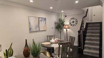 A dining area with a round table, chairs, and a clock on the wall.