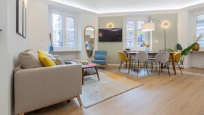 A modern living room with a sofa, chairs, a dining table, and a TV. - Cheerful Apartment XX Settembre by Wonderful Italy (Turin)