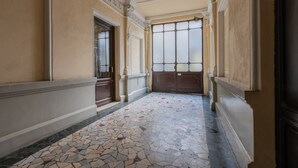 A hallway with a tiled floor, a large wooden door, and a window with frosted glass. - Cheerful Apartment XX Settembre by Wonderful Italy (Turin)
