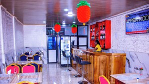 A restaurant with bar seating, a counter, and a television screen. - WEST HOTEL DOUALA  (Bonaberi)
