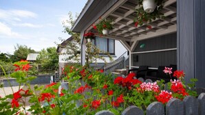 A covered outdoor area with a wooden fence, potted plants, and a building with a grey exterior and a window. - Lochiel Apartment Self Catering (Fort William)