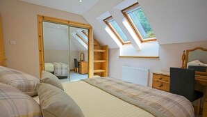 A bedroom with a large bed, a dresser, a mirror, and a skylight. - Lochiel Apartment Self Catering (Fort William)