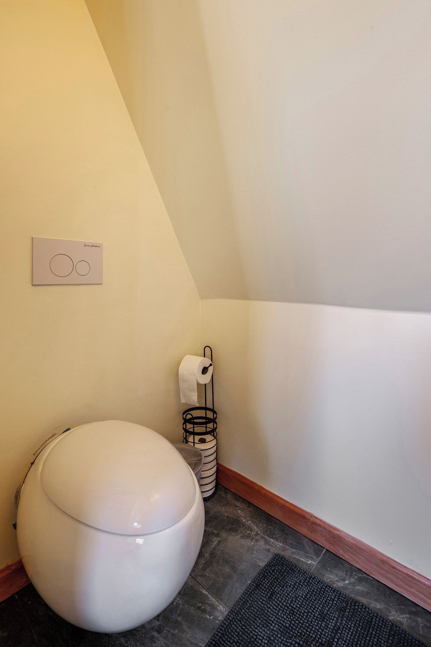 Et lille badeværelse med toilet, papirhåndklædeholder og skraldespand.