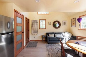 A compact kitchen with a stainless steel refrigerator, wooden cabinets, and a dining area with a table and chairs.