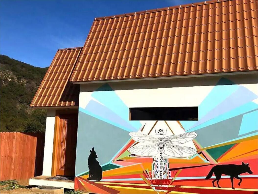 A building with a tiled roof and a colorful mural featuring a wolf, a fox, and a dragonfly.