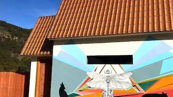 A building with a tiled roof and a colorful mural featuring a wolf, a fox, and a dragonfly.
