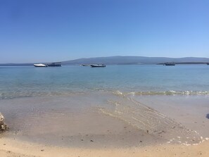 A beach with calm waters, boats, and distant mountains. - Villa Sa Mora: Holiday Home with Sea View, Garden, and Air Conditioning (Mandriola)