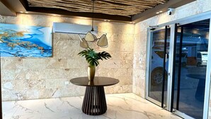 Un hall d’entrée avec une table ronde, une plante en pot, une carte accrochée au mur et une porte en verre.