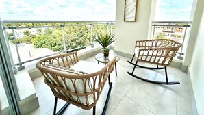 Un balcon agrémenté de meubles en osier, d’une petite table et d’une plante en pot.