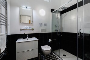 Een badkamer met een wit wastafelmeubel, spiegel, toilet en douchecabine met glazen wanden.