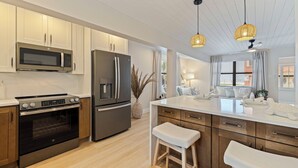 Una cocina moderna con electrodomésticos de acero inoxidable, armarios de madera y una isla central con taburetes.